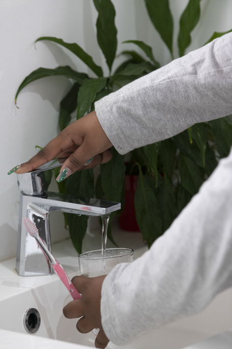 Personne qui se sert un verre d'eau dans la salle de bain